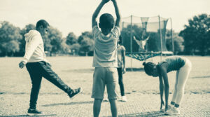 Enfants faisant des exercices d'étirement et d'échauffement dans un parc avant de faire du trampoline.