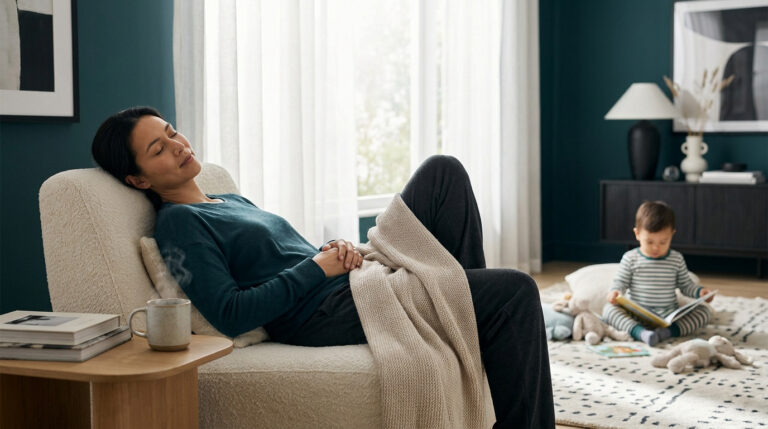 Une mère se repose dans un fauteuil confortable avec un thé, tandis que son bébé joue tranquillement sur le tapis.