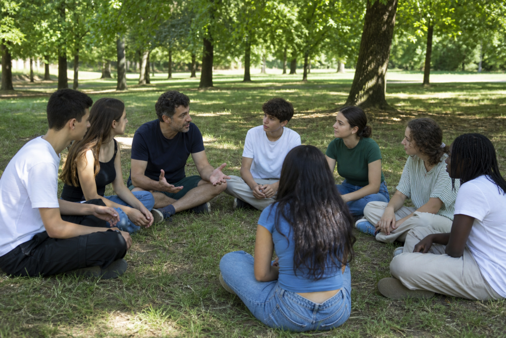 Cercle de jeunes en extérieur avec un animateur jouant calmement sans matériel