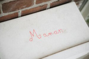 Graffiti rouge Maman écrit à la main sur une marche de pierre claire contre un mur de briques