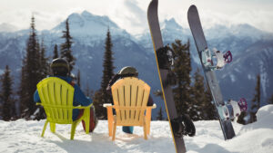Snowboardeurs au repos dans des chaises colorées face aux sommets enneigés, vacances de février en station